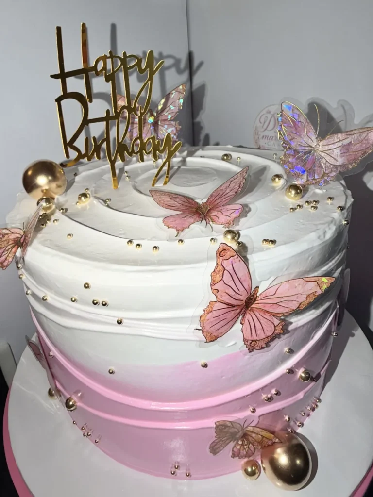 Pink and white Dominican birthday cake with gold butterflies