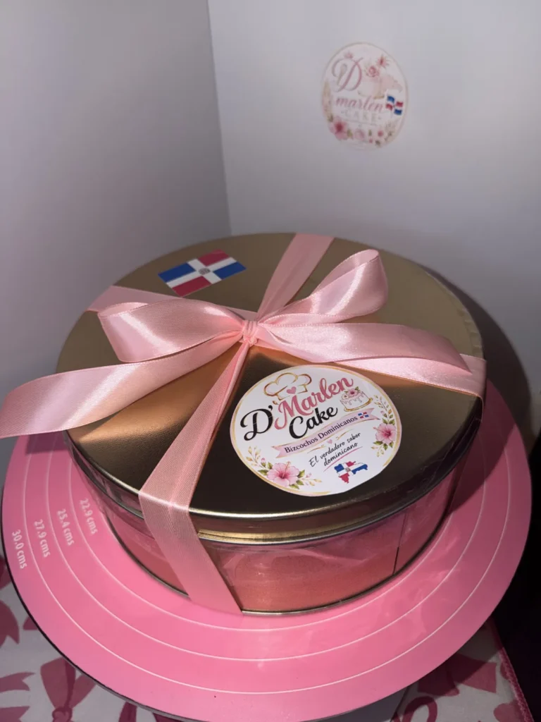 Gold cake tin tied with a pink ribbon and D'Marlen Cake label